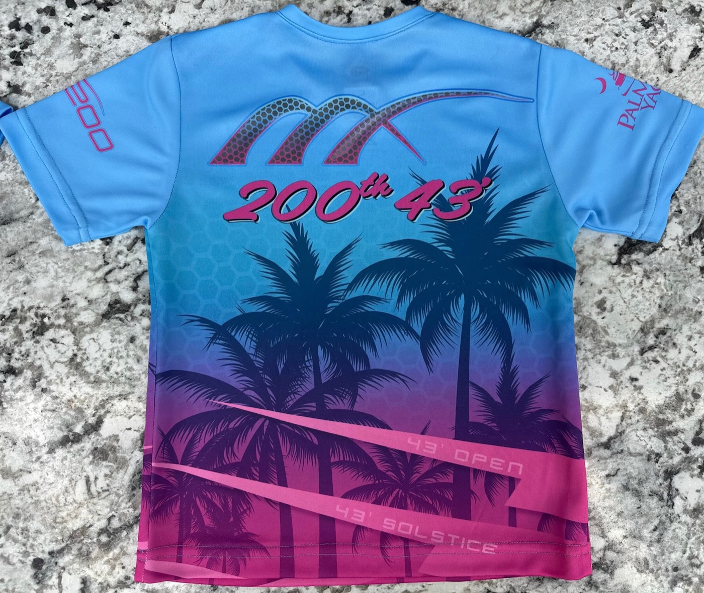 Back of a Midnight Express 200th t-shirt with palm trees in a blue-to-pink gradient